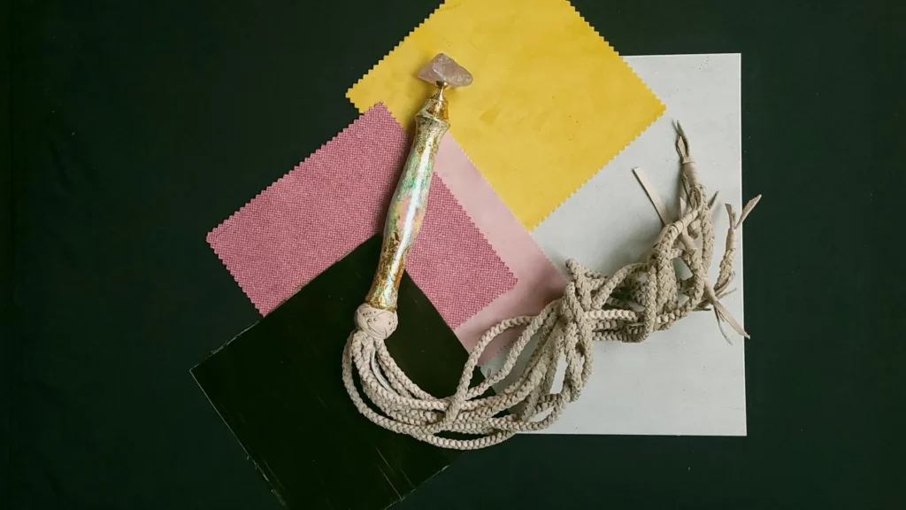 Handgemachter Flogger aus recycelten Materialien auf bunten Stoffmustern