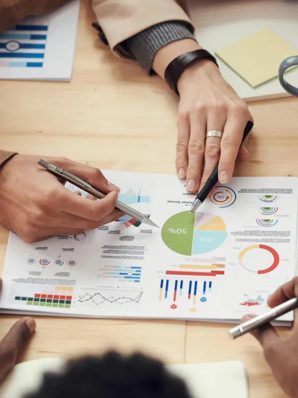 Hände analysieren Affiliate-Daten und Marketing-Diagramme auf Papier