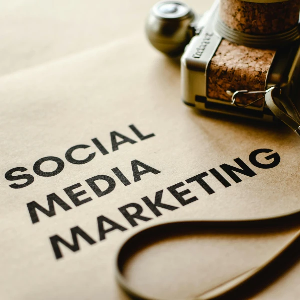 Kamera und Schriftzug „Social Media Marketing“ auf braunem Papier – Symbolbild für Marketingstrategien in der Erotikbranche