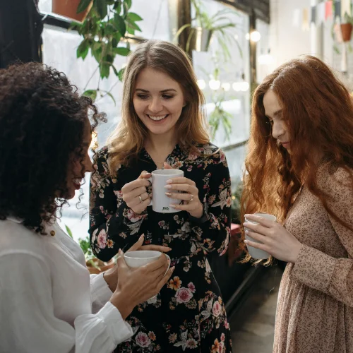 Drei Frauen trinken Kaffee und unterhalten sich in entspannter Atmosphäre