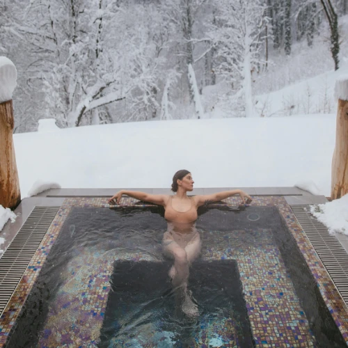 Frau entspannt im Whirlpool vor verschneiter Winterlandschaft