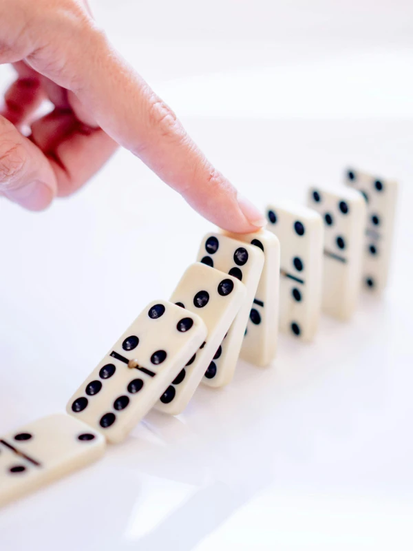 Kosten hängen zusammen Dominoeffekt als Symbol dafür, wie die Kosten für einen Swingerclub zusammenhängen