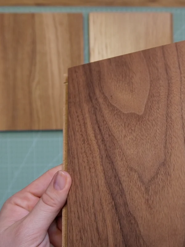 Hand hält Holzmuster in verschiedenen Holzarten für den Bau von BDSM Möbeln