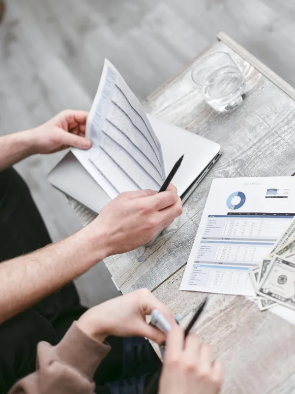 Zwei Personen besprechen Finanzunterlagen und Diagramme beim Gründungsgespräch