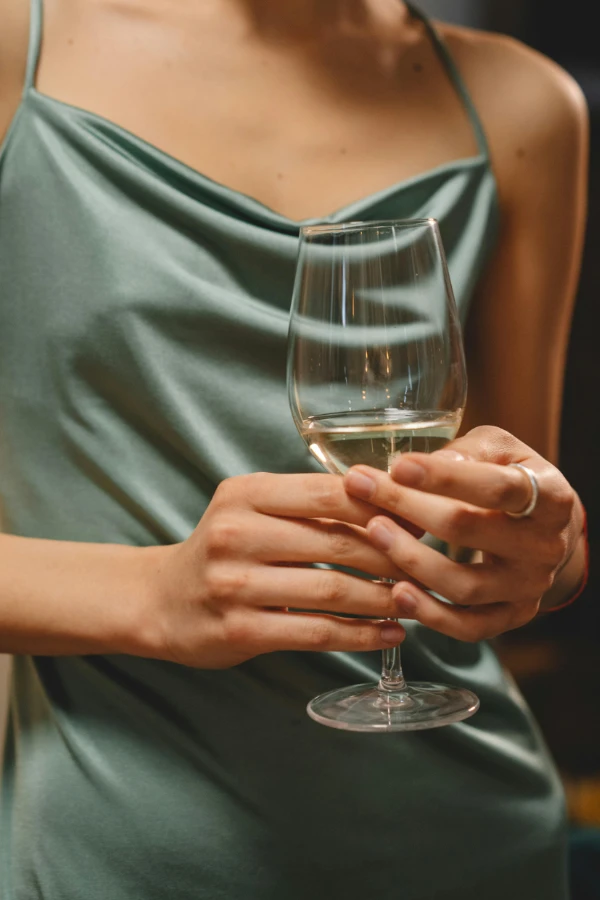 Eine elegante Frau hält ein Weinglas. Das gesamte Bild steht für eine High Class Escort Agentur die von Grietje Concept und Design Beratung erhält.