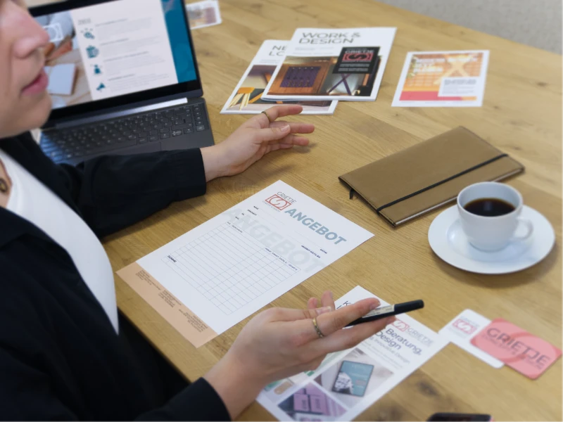 Gründungsberatung Erotikbranche von Grietje Concept Design, Beratungsgespräch mit Angebot, Printmaterialien und Laptop auf dem Tisch
