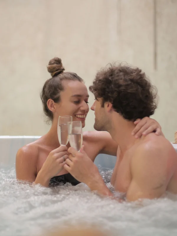 Paar mit Sekt im Whirlpool als Beispiel für das Romantik-Segment im Erotikhotel