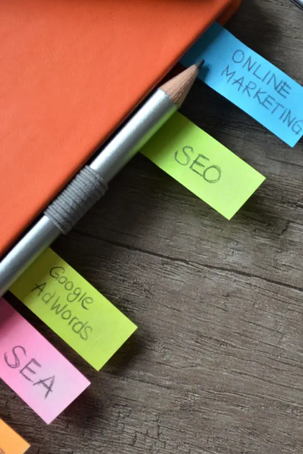 Notizbuch mit bunten Haftnotizen zu Online Marketing und SEO auf einem Holztisch